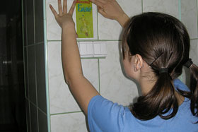  Hanka przykleja naklejkę w szkolnej łazience.
 fot.Koło Ekologiczne Ekozespoły